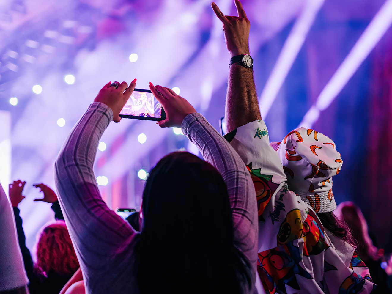A fan holding up a phone to get a photo of the show on the stage at Blossom Music Center.